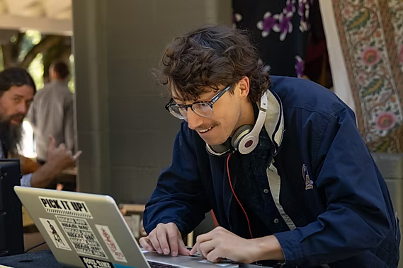 Rob Schenk standing in a garden wearing a patterned shirt and black pants